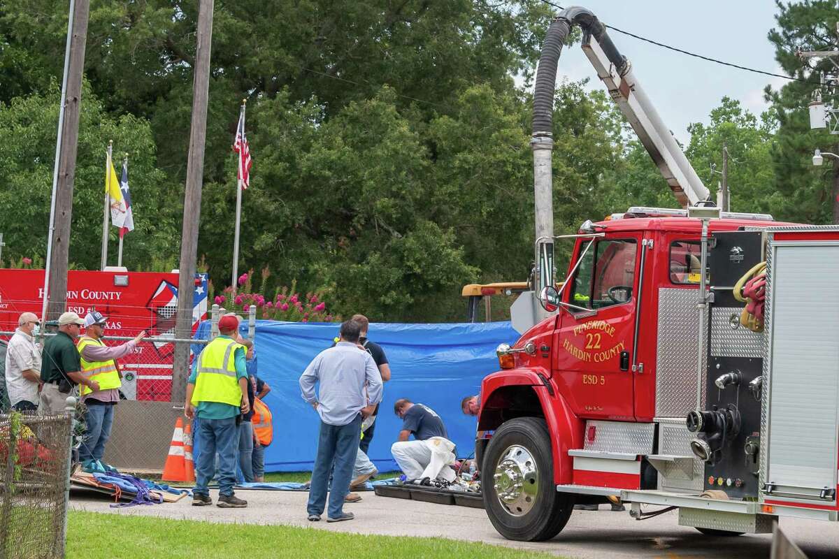 Emergency workers work outside a manhole to support responders in the tunnel below. Two men lost their lives while working underground in the sewer lines at the intersection of West Barkley and Mitchell Streets in Sour Lake on Thursday. Photo made on July 9, 2020. Fran Ruchalski/The Enterprise
