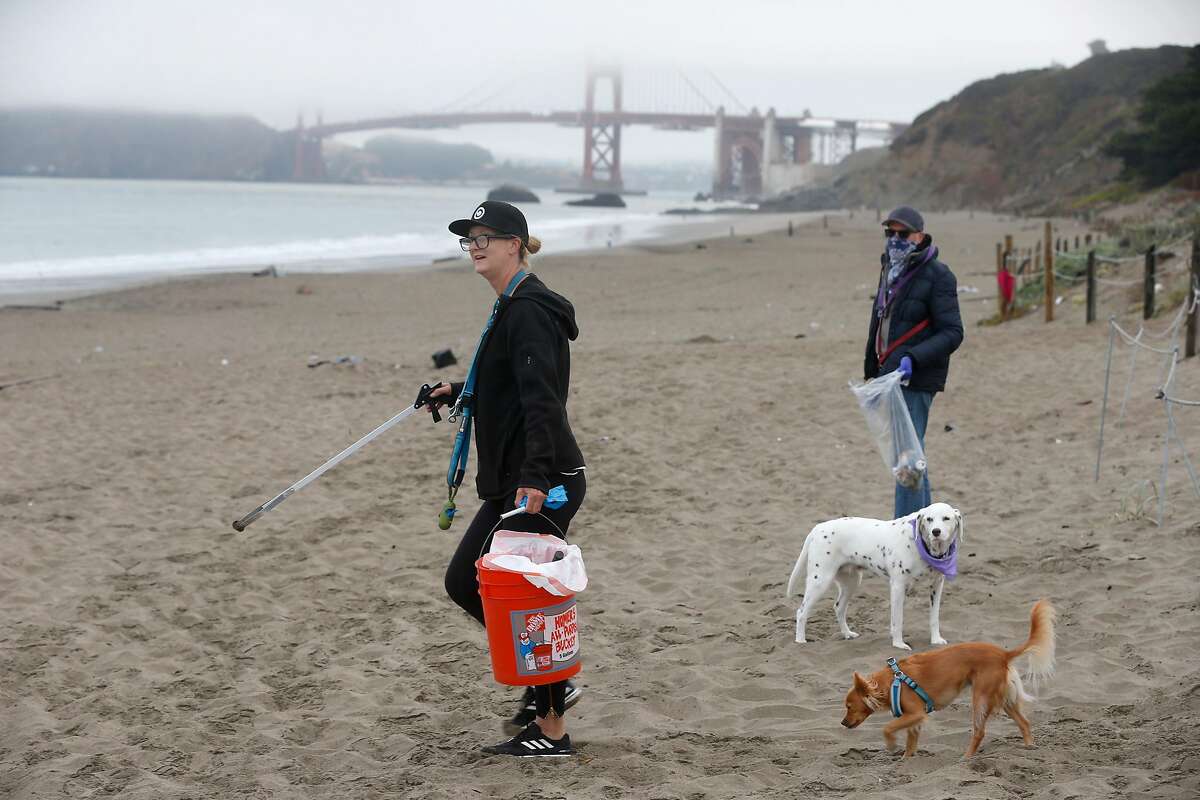 Eva Holman and Randall Fitz collect trash and debris, including PPE, left behind by the previous day's visitors at Baker Beach in San Francisco, Calif. on Tuesday, June 23, 2020.