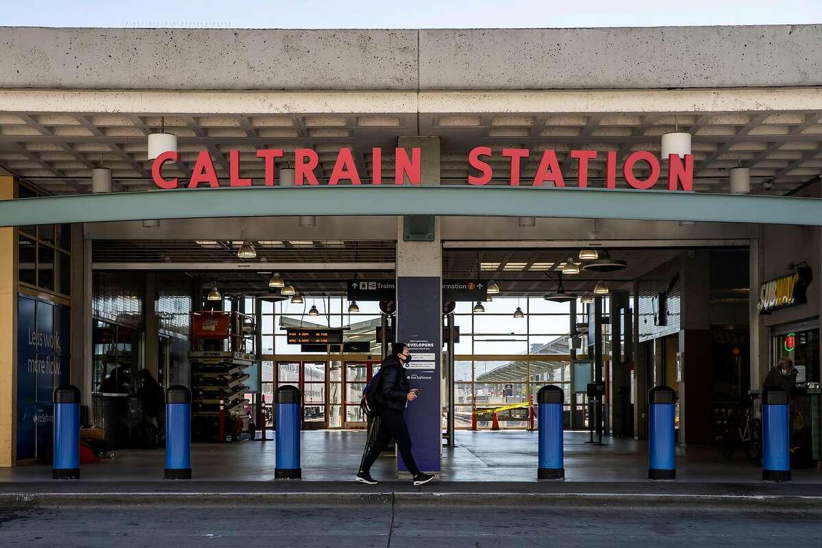 A woman walks past an entrance of the Caltrain Station at King Street and 4th Street on Thursday, July 9, 2020, in San Francisco, Calif. California rolled out its vision for high-speed trains between San Jose and San Francisco on Thursday, plotting a 30 or so minute ride on what would be one of the busiest stretches of the state�s proposed 520-mile rail system. The California High Speed Rail Authority is calling for 220-mph trains, coming from the Central Valley, to merge onto the Caltrain commuter line for a 49-mile jaunt up the Peninsula. Stops would be made at San Jose�s Diridon Station, a new hub in Millbrae and at the Caltrain depot in San Francisco. The San Francisco stop would eventually move to Transbay transit center.