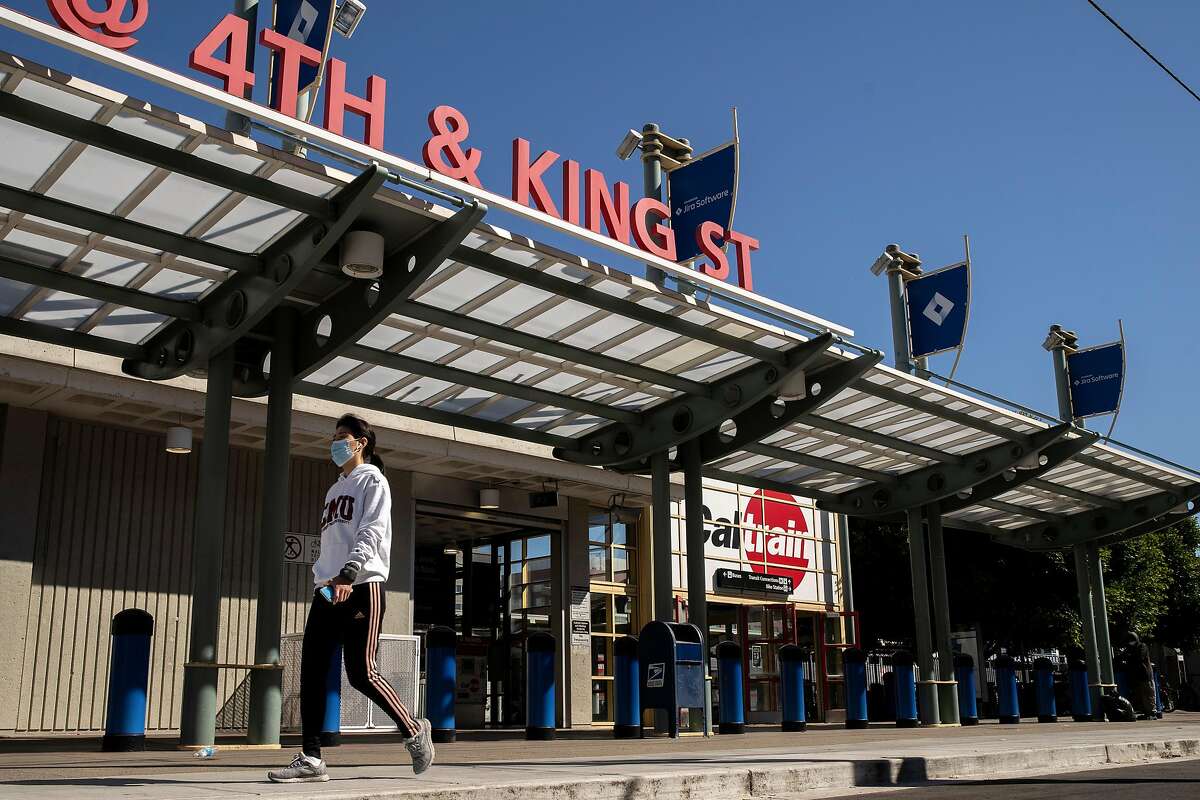 A person walks past the Caltrain Station at King Street and 4th Street on Thursday, July 9, 2020, in San Francisco, Calif. California rolled out its vision for high-speed trains between San Jose and San Francisco on Thursday, plotting a 30 or so minute ride on what would be one of the busiest stretches of the state�s proposed 520-mile rail system. The California High Speed Rail Authority is calling for 220-mph trains, coming from the Central Valley, to merge onto the Caltrain commuter line for a 49-mile jaunt up the Peninsula. Stops would be made at San Jose�s Diridon Station, a new hub in Millbrae and at the Caltrain depot in San Francisco. The San Francisco stop would eventually move to Transbay transit center.