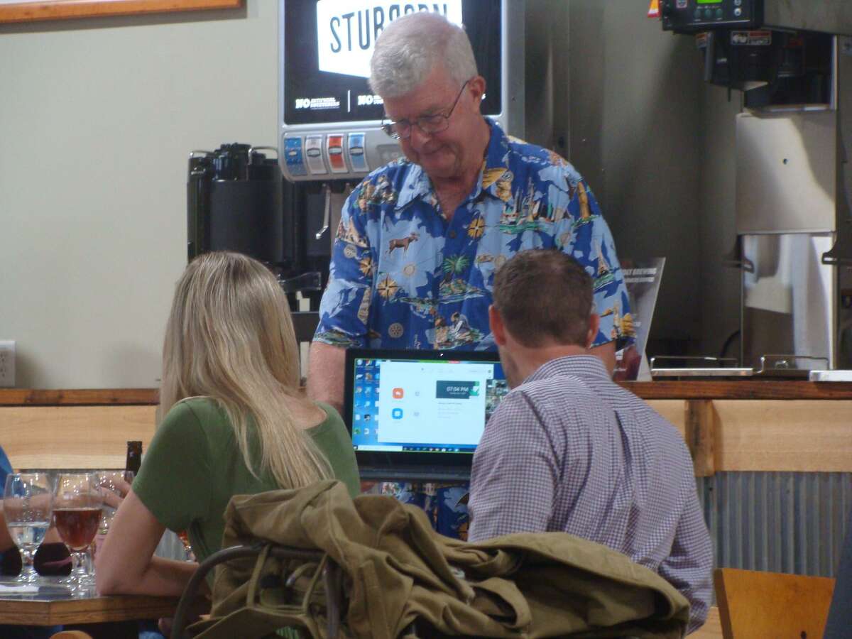Rotary Club of Conroe member Ed Kelly held the laptop and walked it around the room for all of the Zoom participants to say hello to those there in person at the Honor Cafe in Conroe during Tuesday's board installation.