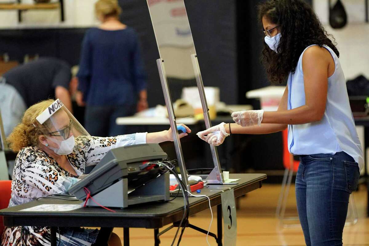Harris County election clerk Nora Martinez, left, helps a voter, Monday, June 29, 2020, in Houston. (AP Photo/David J. Phillip)