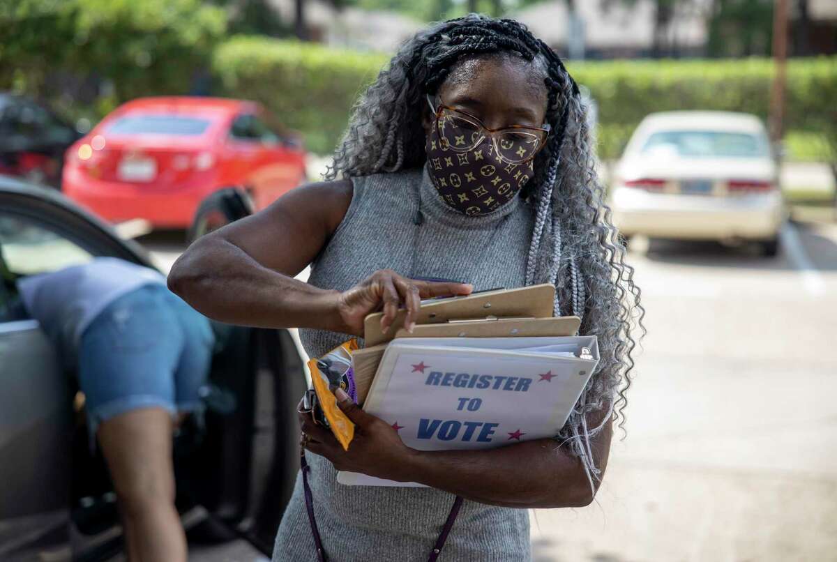 Andrea McWashington with Good Brothers & Sisters of Montgomery County the takes out a voter registration form in Conroe, Thursday, July 9, 2020.