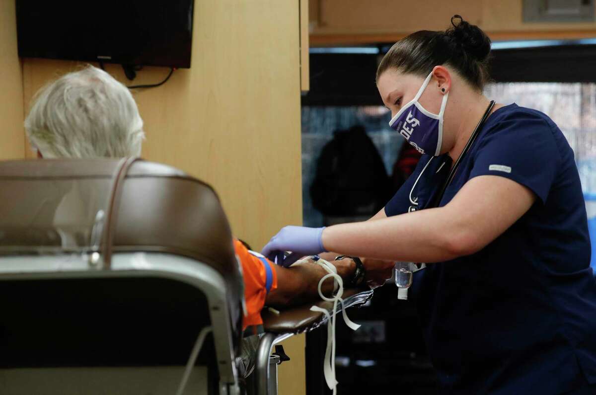Phlebotomist Amanda Butler, right, draws blood from Ben Scarborough during a blood drive Friday in The Woodlands.