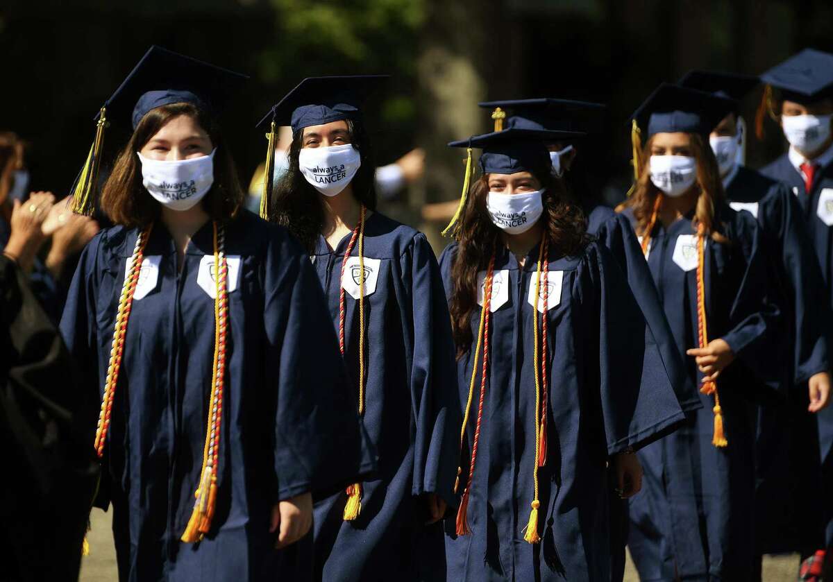 Graduates wear masks reading "Always a Lancer" as they march in to the Notre Dame High School graduation in Fairfield, Conn. on Sunday, July 12, 2020.