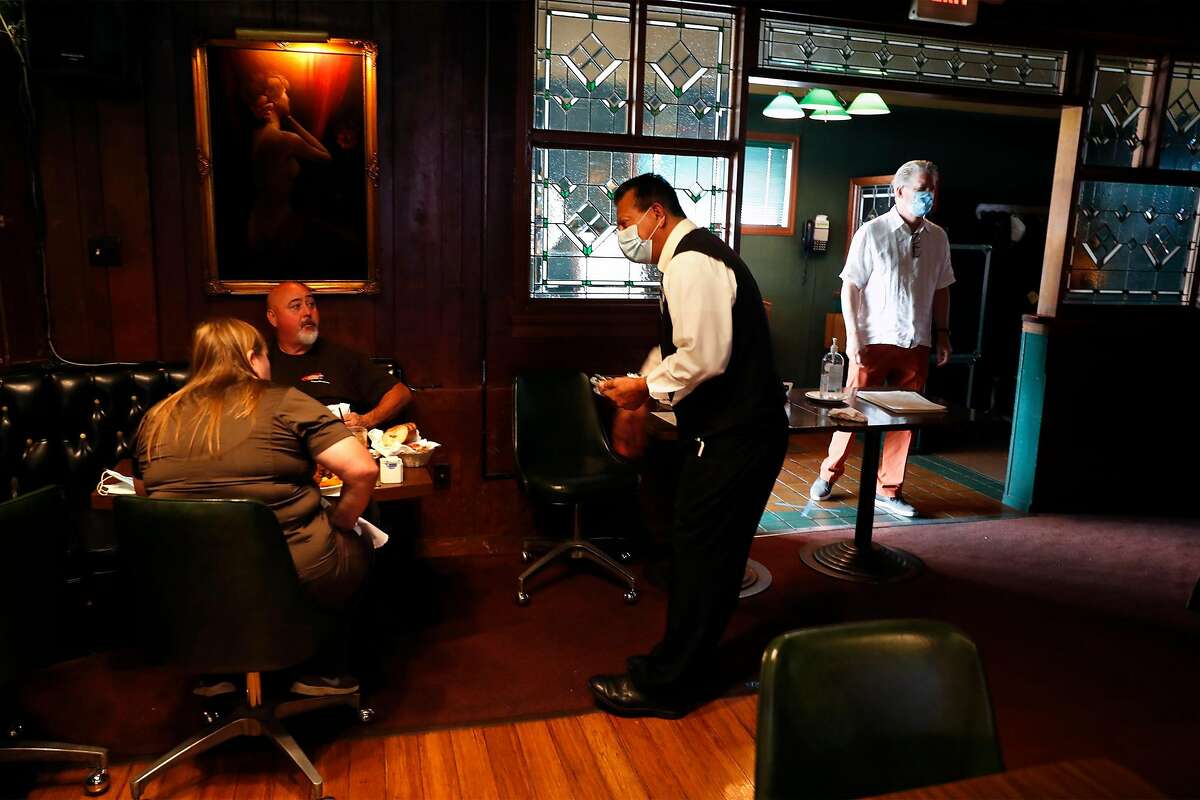 Val's Restaurant & Lounge's Oscar Anaya serves diners as co-owner Jeff Taylor (right) walks by in Daly City, Calif., on Monday, July 13, 2020. Earlier in the day, California Governor Gavin Newsom every county in California to close indoor restaurants, movie theaters and wineries.