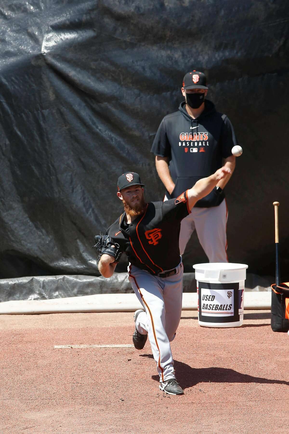 Conner Menez (front) of the San Franciosco Giants pitches in the bullpen during practice at Oracle Park on Monday, July 13, 2020 in San Francisco, Calif.