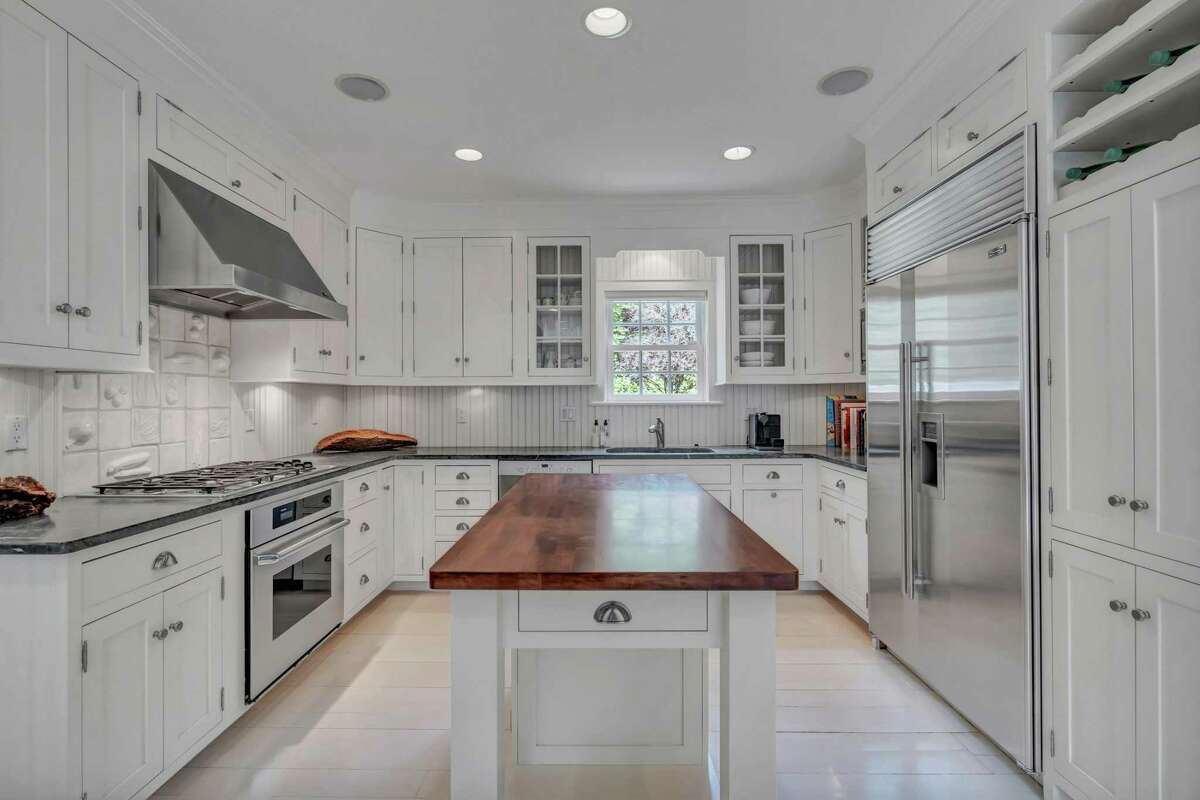 The renovated chef's kitchen features extensive custom cabinetry, a built-in wine rack, granite counters, upscale finishes and a light-filled casual dining area. The renovated chef's kitchen features extensive custom cabinetry, a built-in wine rack, granite counters, upscale finishes and a light-filled casual dining area with French doors leading to the deck and garden. The eat-in section also has a wet bar and a beverage refrigerator. On the second floor there are four bedrooms, including the master suite which features a fireplace, walk-in closet, sitting area, French doors to a private balcony/deck, and private bath with a jetted tub.