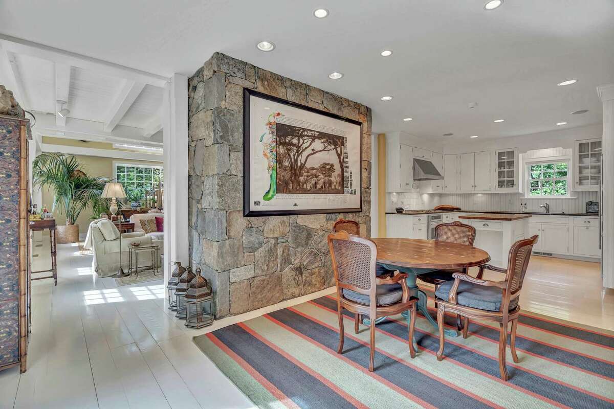 The eat-in section of the kitchen is open to the spacious living or great room. This converted barn is set back behind stacked stone walls and sits on a corner lot of almost a half an acre in the Compo Beach section of Westport. The house is within walking distance of Compo Beach, Ned Dimes Marina and Longshore Club Park, where residents can swim, picnic, golf, play tennis, boat, paddleboard, and engage in other activities at those municipal venues. Multi-paned glass French doors framed by sidelights and a transom open to reveal the 2,998-square-foot house, where there are wide-planked hardwood floors. Another door in the stone portion of the house opens into a foyer with a slate floor. In the cavernous 725-square-foot, two-story living room, which is really more like a great room, there is a wood-burning stone fireplace, built-in shelving, and vaulted ceiling. The family room features a red brick fireplace, built-in desk area with cabinetry, a wall of built-in bookshelves, and French doors to the raised deck.