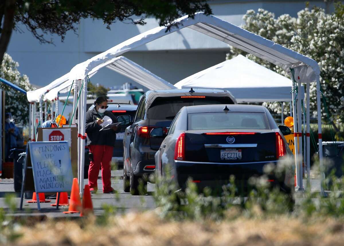 A healthcare worker speaks with a driver arriving for a drive-thru coronavirus test in Concord, Calif. on Tuesday, July 14, 2020.