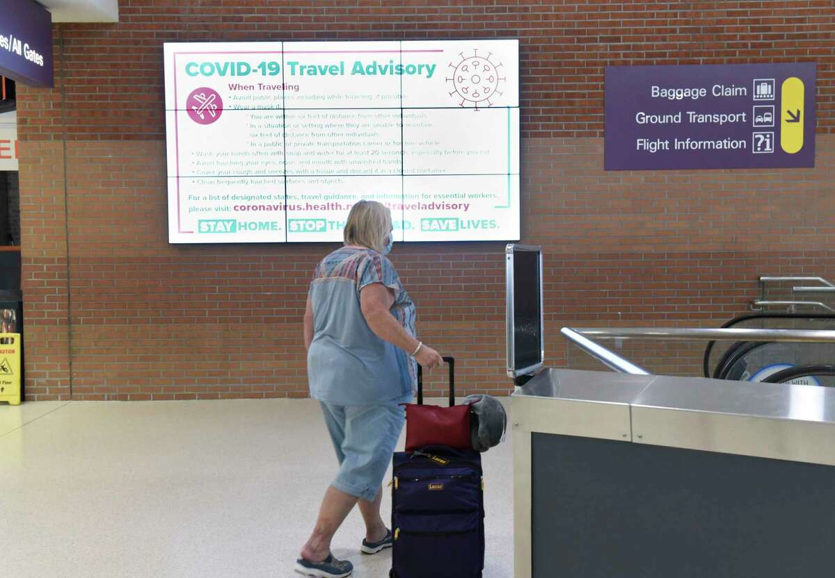 A changing advertisement monitor shows a COVID-19 Travel Advisory at the Albany International Airport Tuesday, July 14, 2020 in Colonie, N.Y. Health Department officials have people fill out forms if they're arriving from Covid hotspot states.(Lori Van Buren/Times Union)