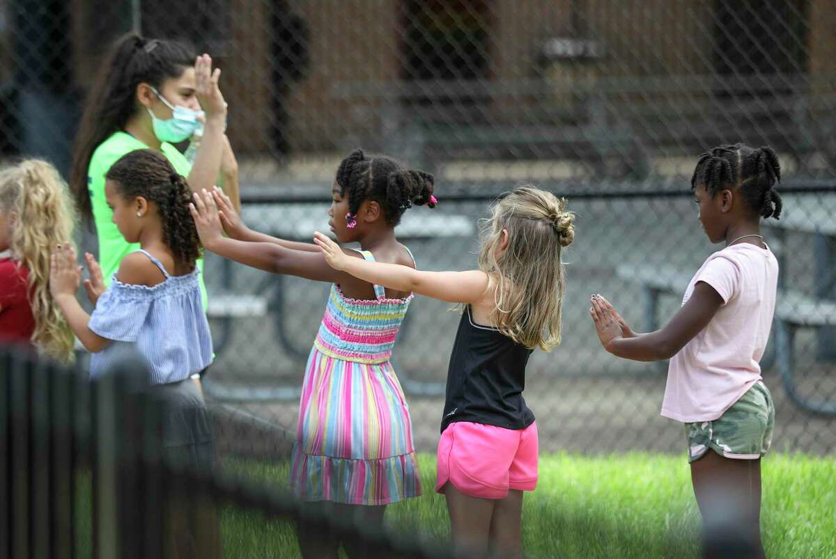 Children line up and practice social distancing as they prepare to go inside Tuesday, July 14, 2020, at the Quillian Center in Houston.