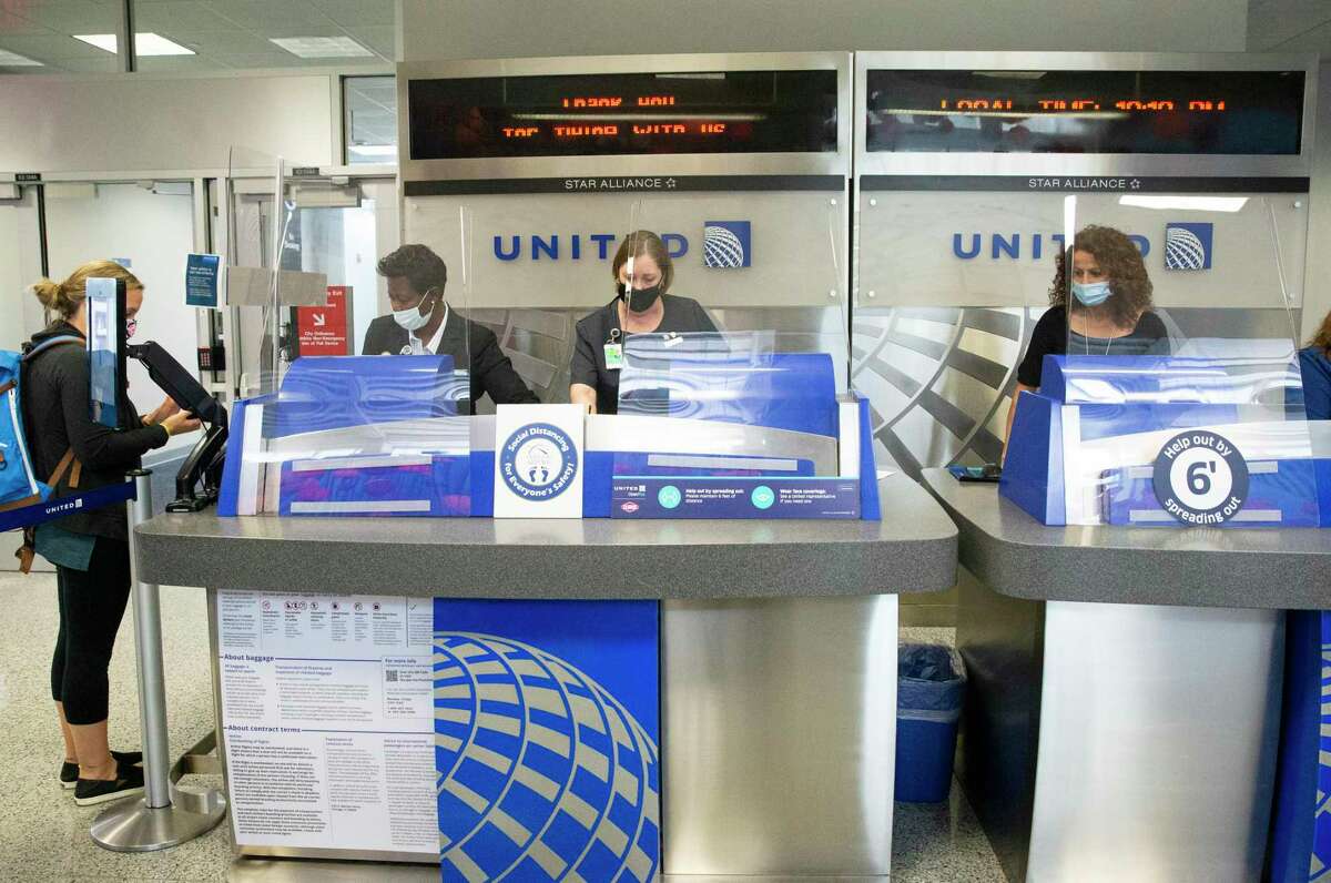 United Airlines customer service representatives help passengers at the boarding gate Tuesday, July 7, 2020, at George Bush Intercontinental Airport in Houston. United Airlines warned it may layoff as many as 3,900 employees at IAH beginning Oct. 1.