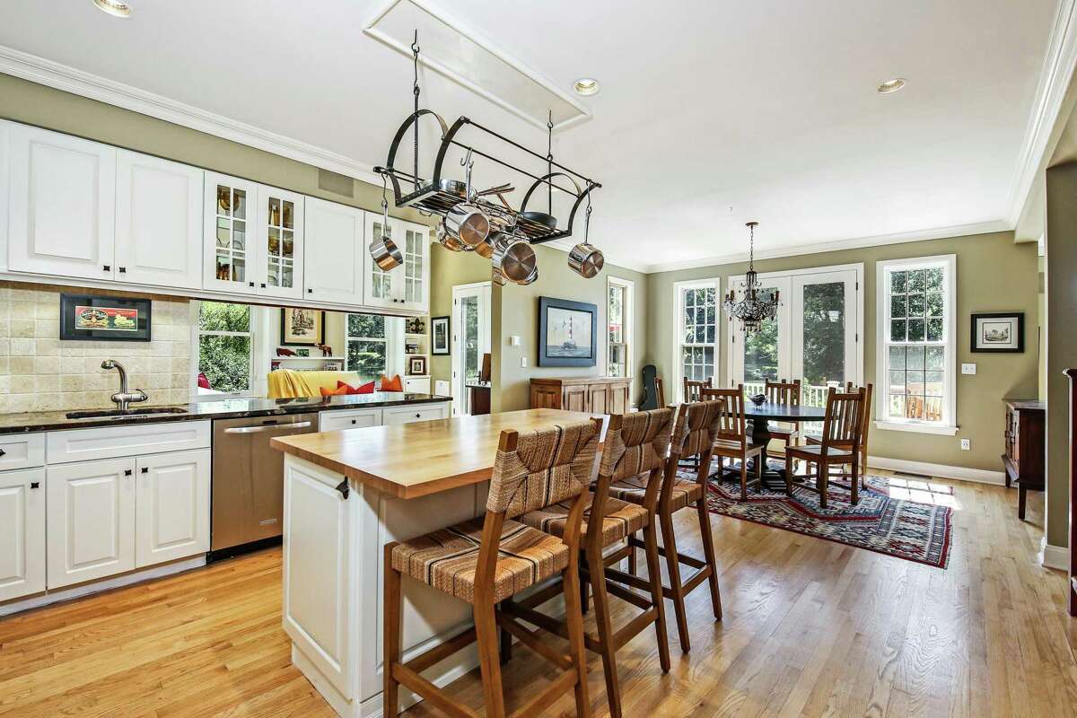 In the chef's eat-in kitchen there is a center island/breakfast bar topped with butcher block, a suspended pot rack, granite counter-tops, tile backsplash, and plentiful cabinetry - some crowned with transom windows and some floating and containing glass doors. High-end stainless steel appliances include a GE Monogram refrigerator/freezer, five-burner DCS gas range, and a garbage disposal. The very spacious dining area has French doors to the deck.