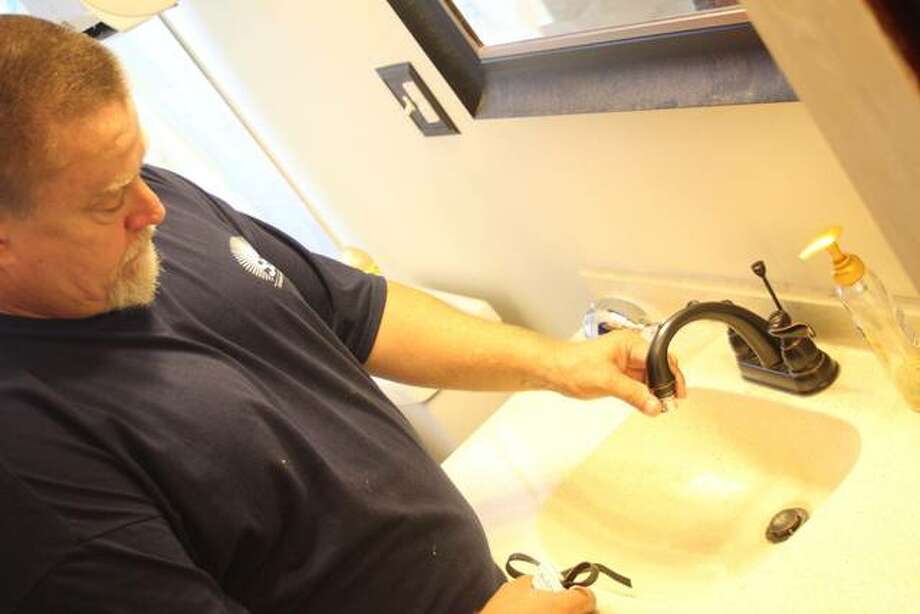 An employee of Senior Services Plus’ handyman program does a small plumbing repair at a senior citizen’s home. Photo: For The Telegraph