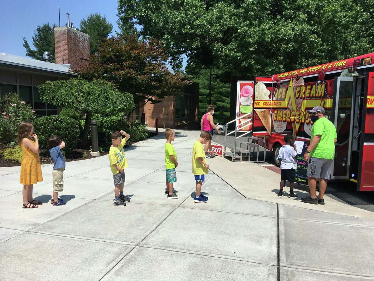 During the age of the coronavirus, children attending Camp Looper wait their turn for ice cream.