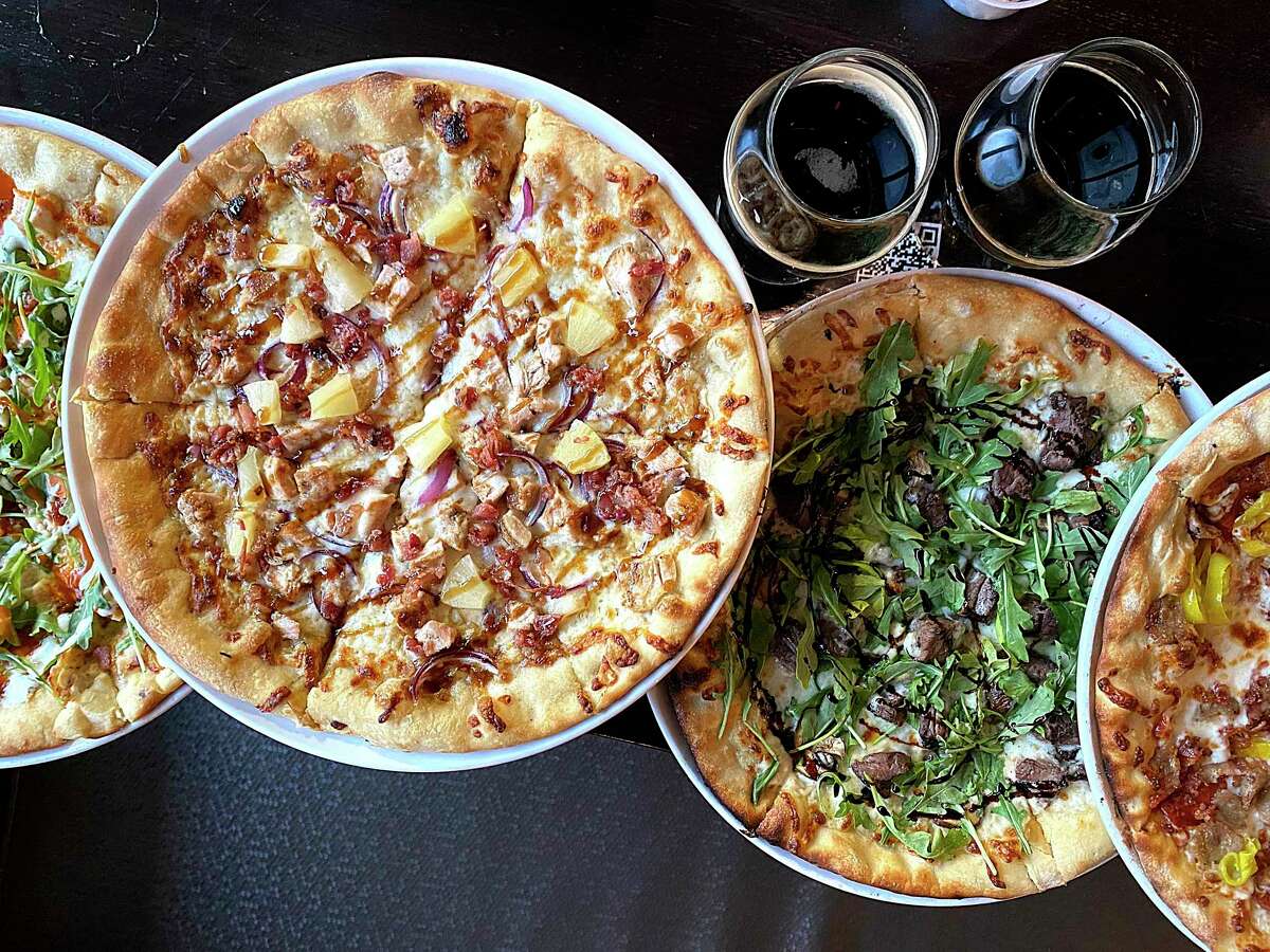 Pizza options include, from left, Buff Chick (Buffalo chicken, bacon, white sauce, arugula, ranch dressing), Maui Waui (chicken, pineapple, bacon, teriyaki sauce), S&M (steak, mushroom, white sauce, arugula, balsamic reduction) and Butchers Block (Italian sausage, pepperoni, bacon, pepperoncini) at Embers Wood Fire Kitchen & Tap in Stone Oak.