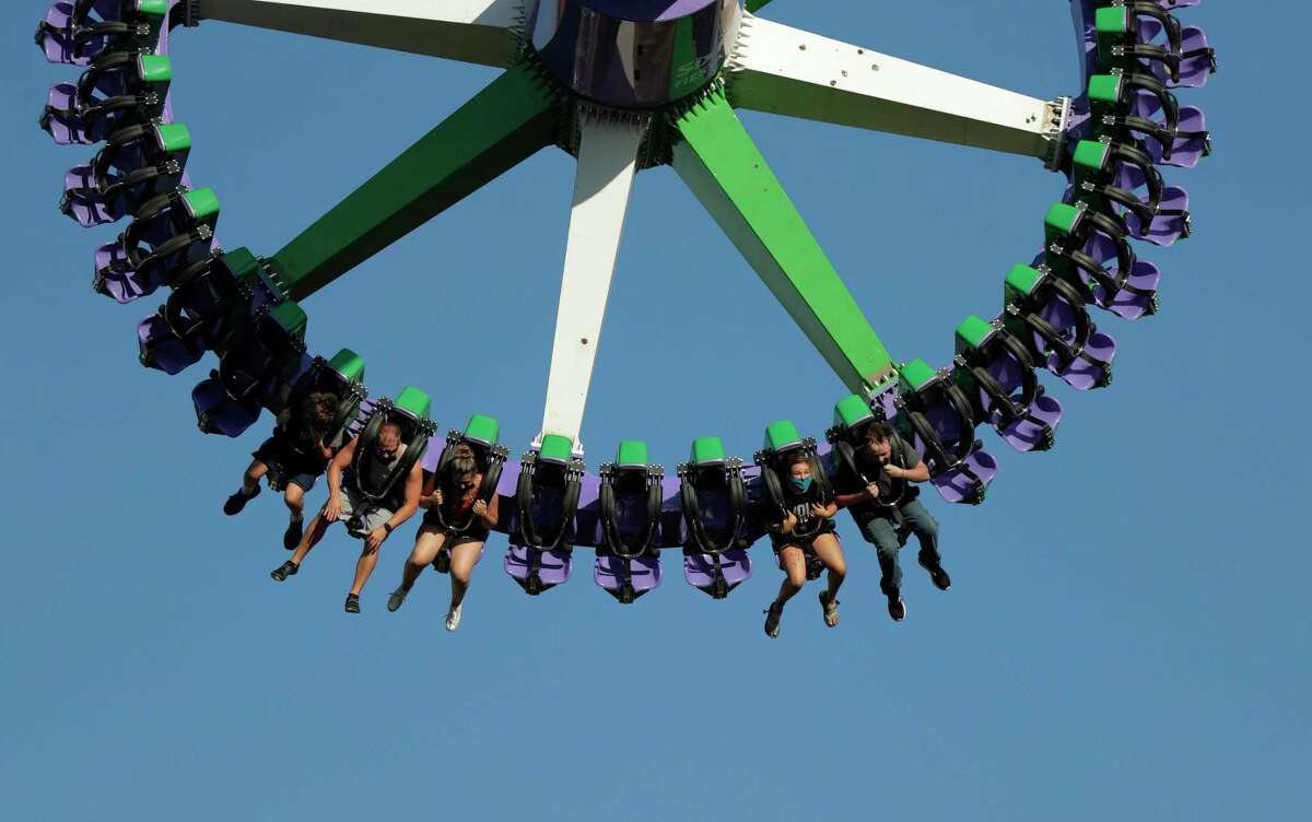 Visitors to Six Flag Fiesta Texas wear masks and maintain social distance as they dangle from the Joker Carnival of Chaos pendulum ride on June 19. The novel coronavirus continues its deadly course; another seven deaths were reported Wednesday. Amusement parks are exempt from state and local orders prohibiting gatherings of 10 or more people, designed to help keep the virus from spreading, but visitors ages 2 and older are required to wear masks and must keep at least 6 feet away from others not in their household. Everyone in Bexar County must wear masks when they’re out in public.