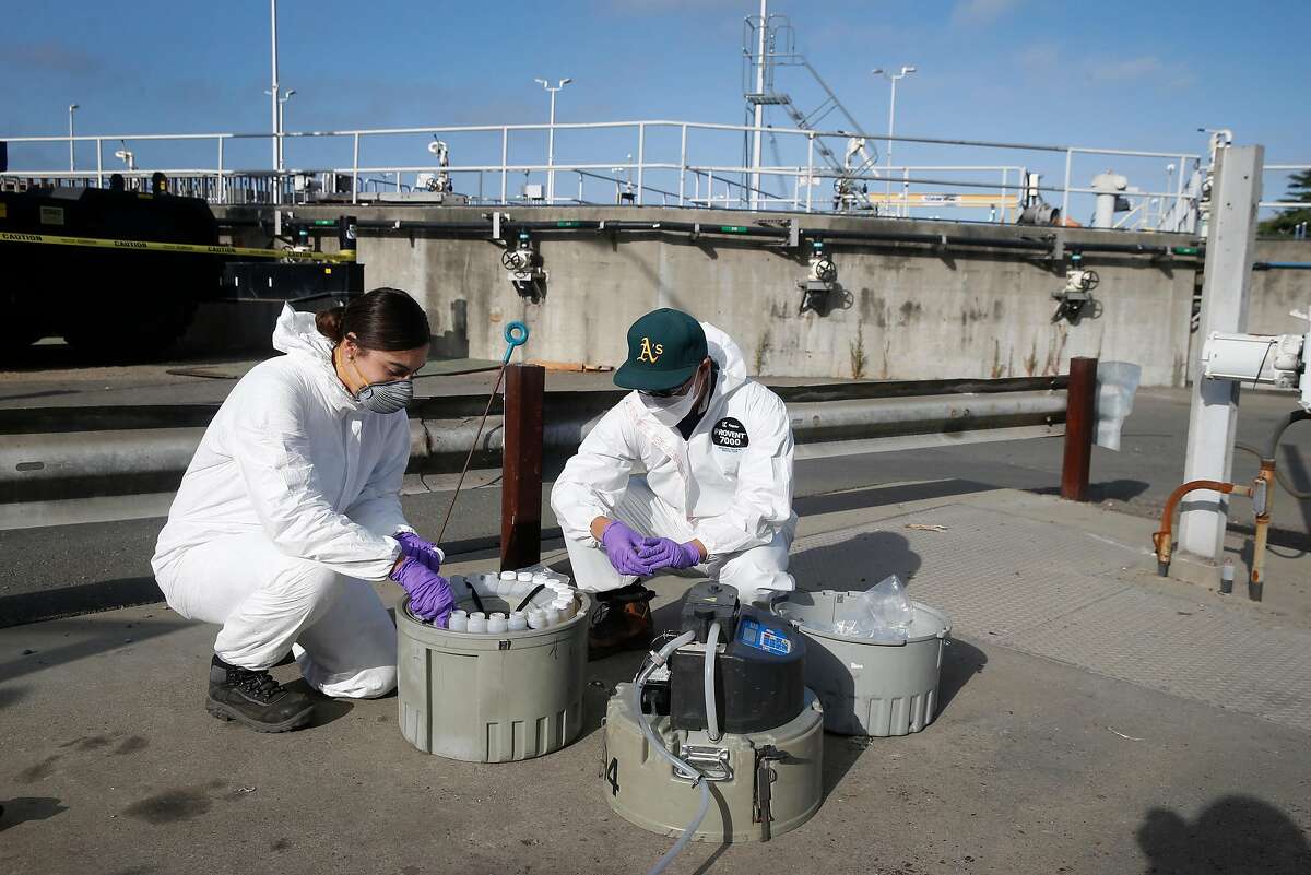 Gabriela Esparza and Zach Wu, wastewater control inspectors with EBMUD, cap 24 separate bottles while retrieving collection equipment and the samples in Oakland, Calif. on Tuesday, July 14, 2020. The samples are sent to a number of labs to analyze for any detection of the COVID-19 coronavirus in the sewage system.