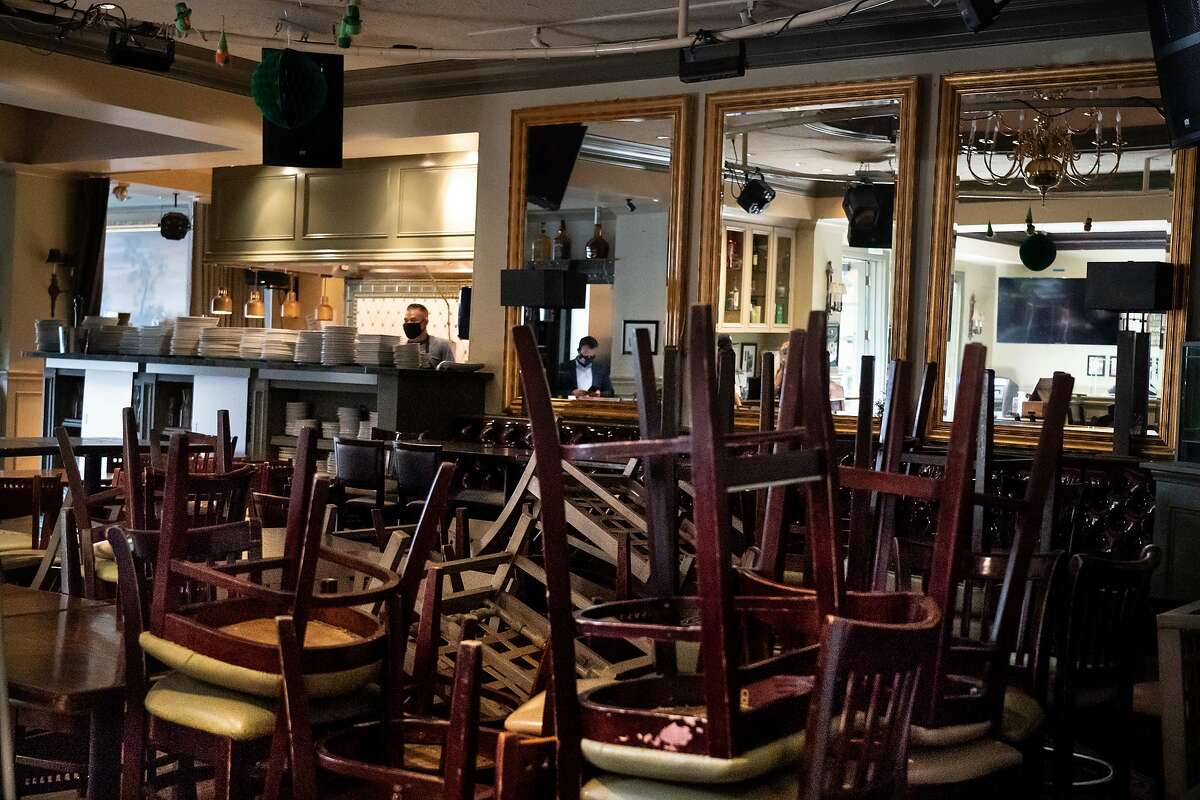 Chef Jorge Carmona works in the kitchen behind stored chairs in the restaurant of Rosie McCann's at Santana Row on Wednesday, July 15, 2020 in San Jose, Calif. They are not allowed to have indoor dining.