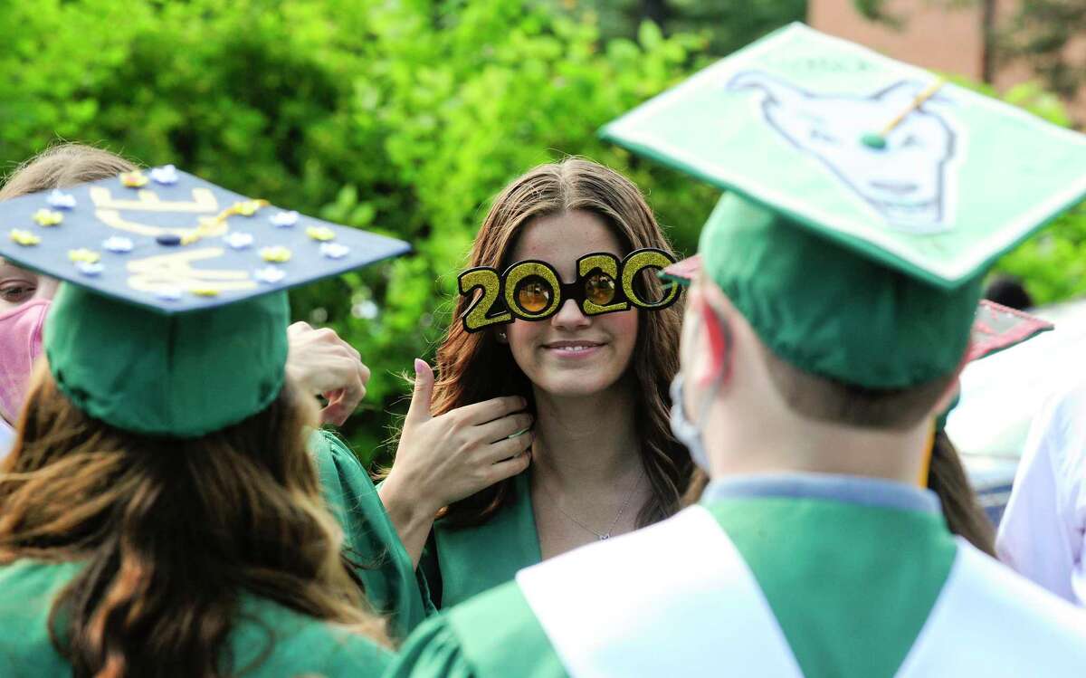 Mackenzie Kuehn, center, gives a thumbs up as she chats with fellow graduates prior to Trinity Catholic High School’s final graduation ceremony on July 16, 2020 in Stamford, Connecticut. Trinity Catholic opened its doors in 1958 as Stamford Catholic High School and the first graduating class was in 1960. The Class of 2020 is comprised of 84 graduates, representing Stamford and its surrounding towns, as well as international students from China.