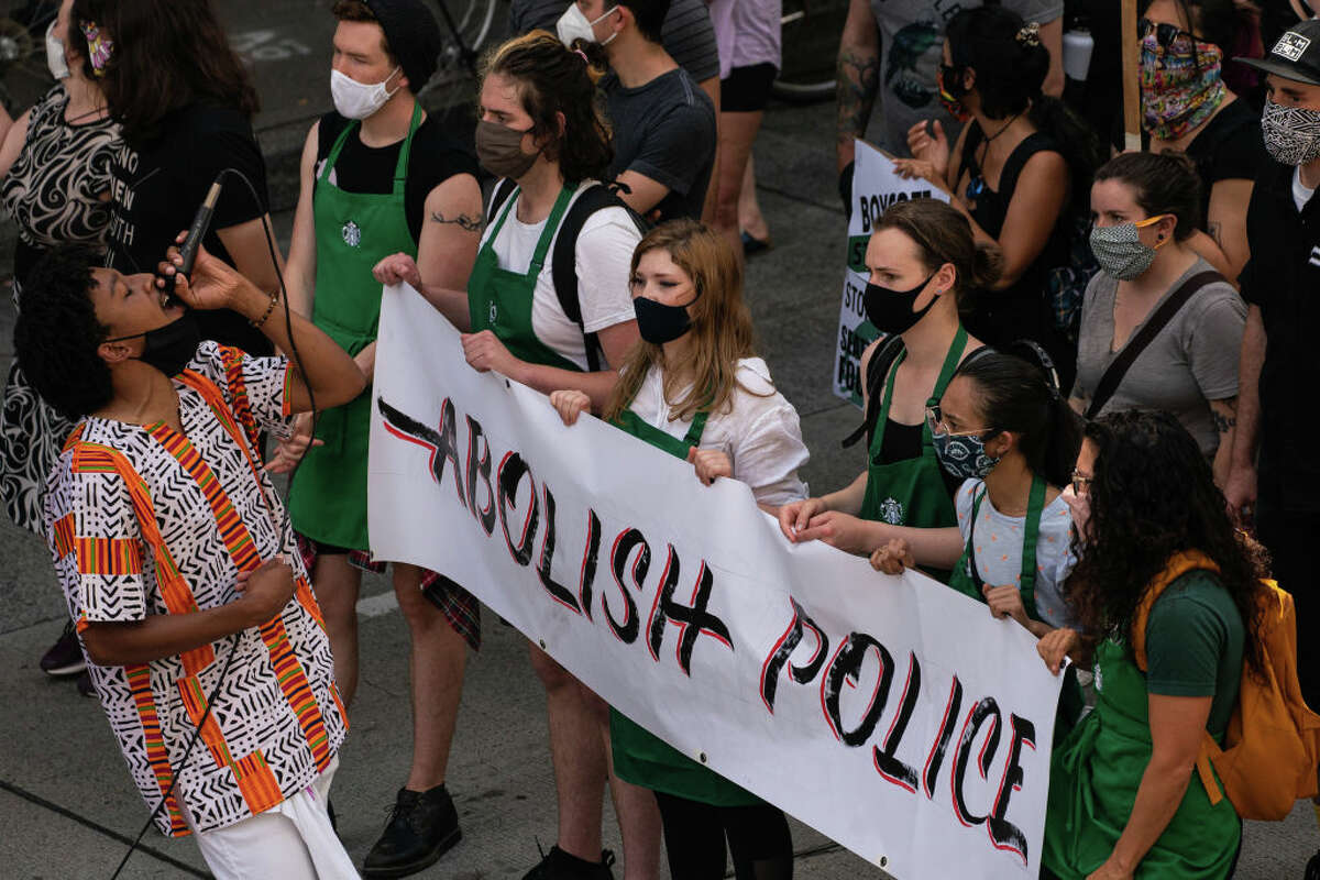 SEATTLE, WA - JULY 16: Protesters march outside a Starbucks location downtown calling for the barista's divestment from the Seattle Police Foundation on July 16, 2020 in Seattle, Washington. The march began at the original Starbucks location in Pike Place Market, stopping at several locations in the city before finishing at the upscale Starbucks Reserve Roastery in the Capitol Hill neighborhood. (Photo by David Ryder/Getty Images)