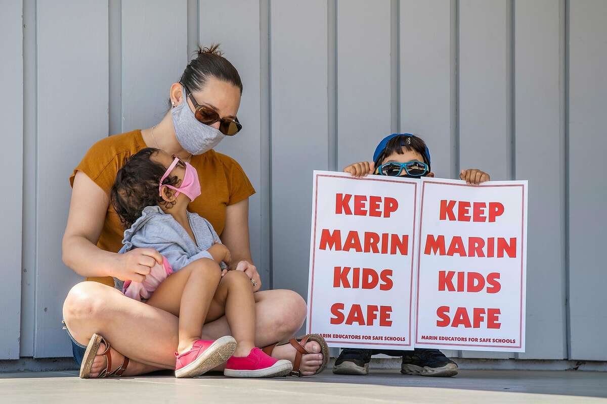 From left: Beverly Chakrabarty with her children Leena Chakrabarty, 3, and Kavish Chakrabarty, 7, listen in during a rally outside the Marin County Office of Education on Thursday, July 16, 2020, in San Rafael, Calif. Teachers and their supporters across California are protesting school district plans for in-person learning, amid the coronavirus pandemic. Chakrabarty said she is a parent supporting the protest.
