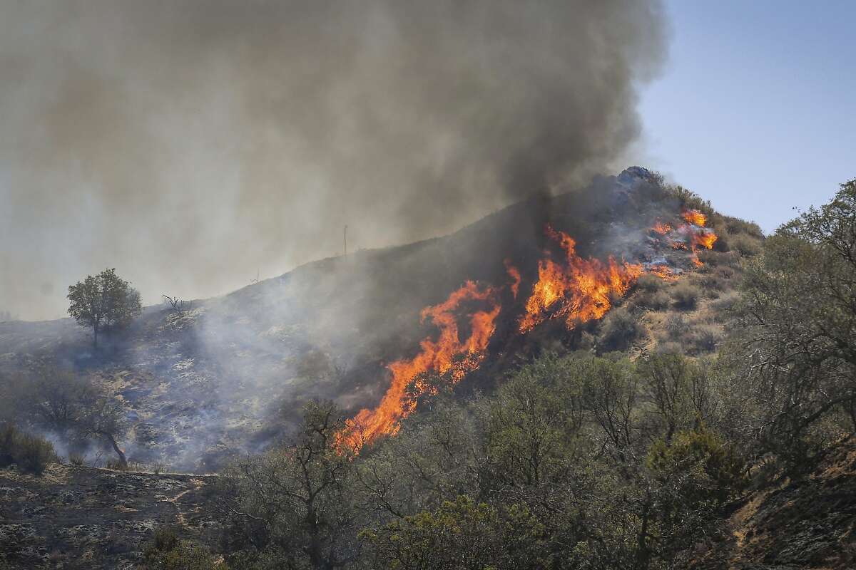 Flames erupt on a hillside along Mineral Spring Road west of Coalinga, Calif., at the Mineral Fire on Thursday, July 16, 2020. Firefighters aided by helicopters and air tankers battled a 26 square mile (66.7 square kilometers) wildfire in a rural area of Central California that is 20% contained, a fire command statement said. (Craig Kohlruss/The Fresno Bee via AP)