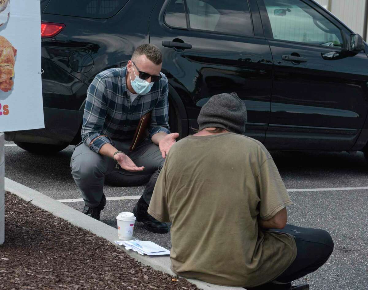Justin Cullmer, New Milford Police community care coordinator, talks with a client in the parking lot of a local food business. Wednesday, July 15, 2020, in New Milford, Conn.