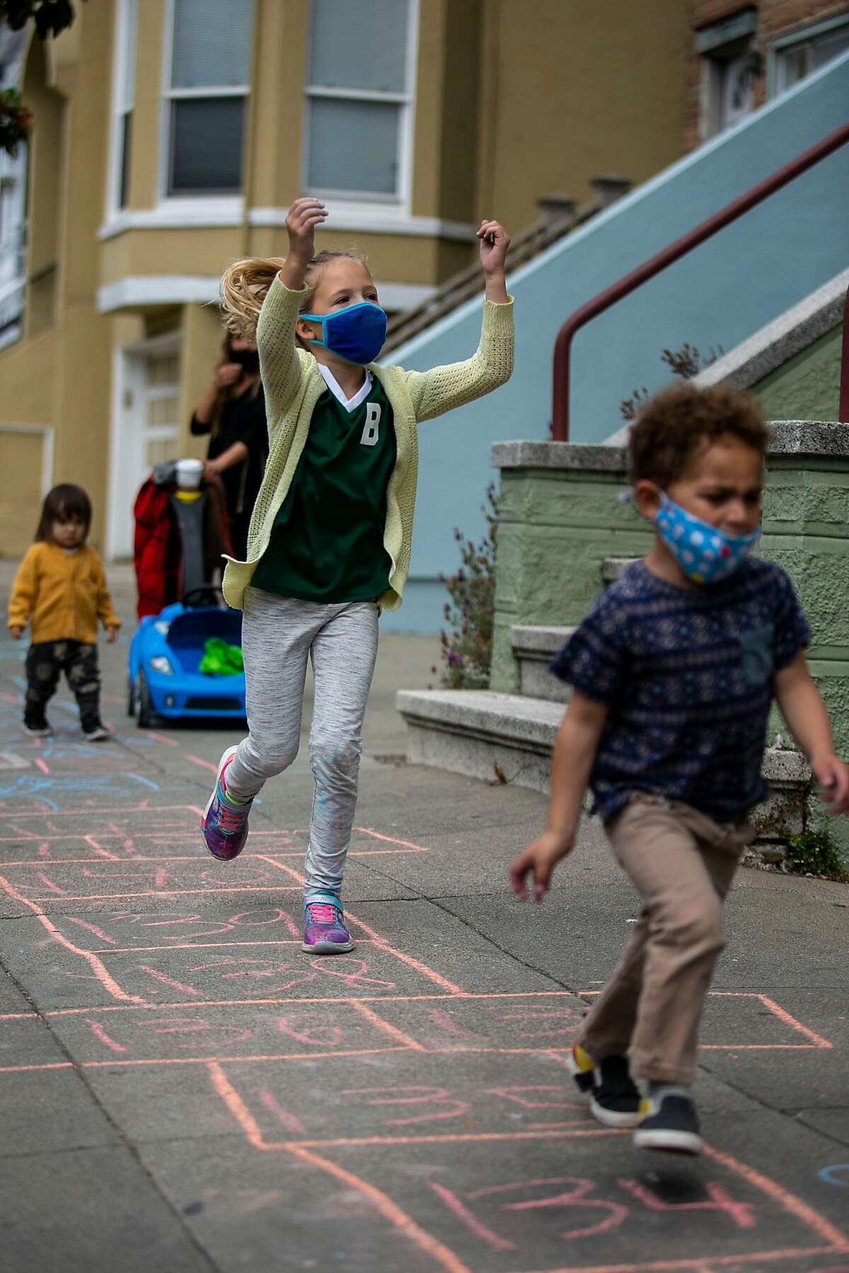 Quin Delaplane, 7, follows Two Chima, 3, as they test out their section of a hopscotch course along Fulton Street during the Hopscotch Your Block event on Saturday, July 17, 2020 in the North of Panhandle neighborhood of San Francisco, Calif. The event, organized by the North of Panhandle Neighborhood Association, aimed to create a physically distanced and synchronized four mile long hopscotch course through the neighborhood.