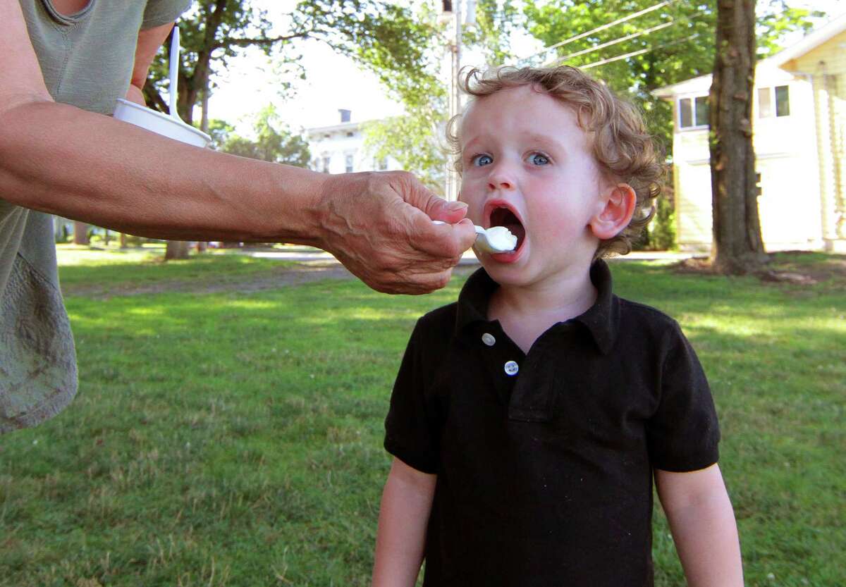 Dori DeCarlo gives her grandson Danny, 2, a spoonful of ice cream while spending some time in the shade on Paradise Green in Stratford, Conn., on Saturday July 18, 2020.