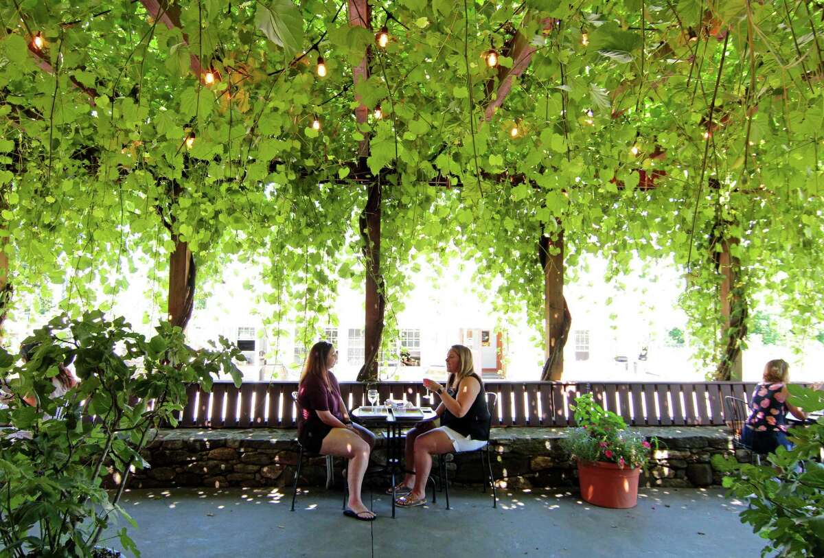 Tiffany DeMica, of Danbury, and her friend Kristen Commander, of Shelton, at right, enjoy wine on the shaded terrace at Jones Winery at Jones Family Farm in Shelton, Conn., on Saturday July 18, 2020.