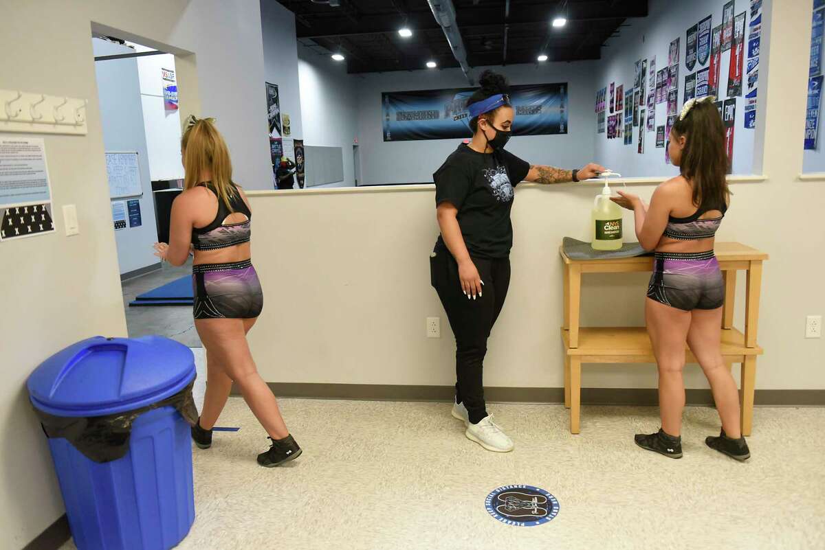 Alex Joslyn, 15, of Latham, left, and Miranda Diaz, 14, of Albany, get their hands sanitized again as they enter the gym area during tryouts for the group's hip-hop competitive team at Premier Cheer Academy on Friday, July 17, 2020 in Albany, N.Y. (Lori Van Buren/Times Union7