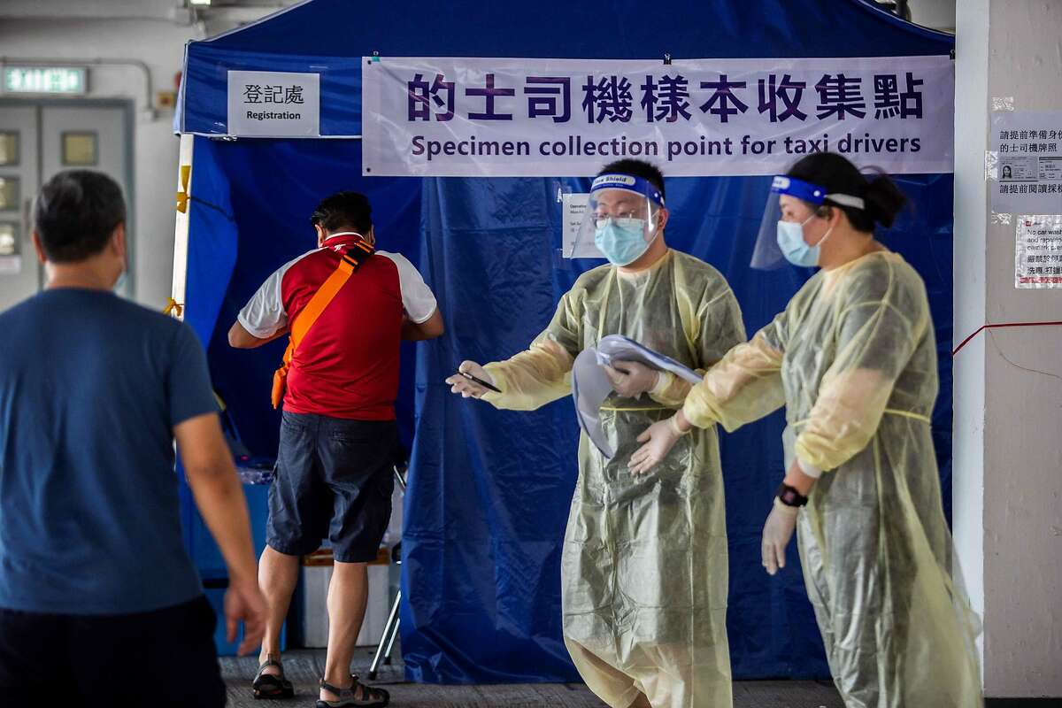 A taxi driver (2nd L) arrives to get tested for coronavirus COVID-19 at a makeshift testing station in a carpark in Hong Kong on July 19, 2020. - The deadly coronavirus is spreading out of control in Hong Kong with a record 100 new cases confirmed, the finance hub's leader said as she tightened social distancing measures to tackle the sudden surge in infections. (Photo by ISAAC LAWRENCE / AFP) (Photo by ISAAC LAWRENCE/AFP via Getty Images)