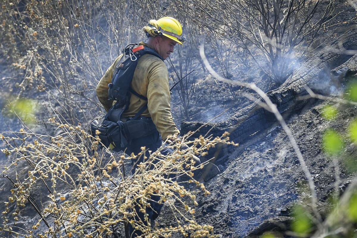A firefighter works to knock down hot spots on a hillside along Mineral Spring Road west of Coalinga, Calif., while fighting the Mineral Fire on Thursday, July 16, 2020. Firefighters aided by helicopters and air tankers battled a 26 square mile (66.7 square kilometers) wildfire in a rural area of Central California that is 20% contained, a fire command statement said. (Craig Kohlruss/The Fresno Bee via AP)