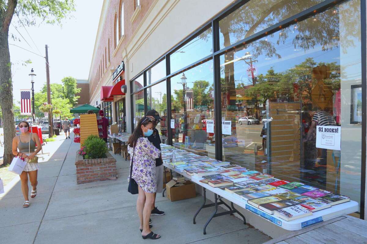 Carin Jamieson and Ed Caliri of Newtown check out the books outside of the Fairfield University Bookstore at the annual Sidewalk Sale & Street Fair on Saturday, July 18, 2020, in Fairfield, Conn.