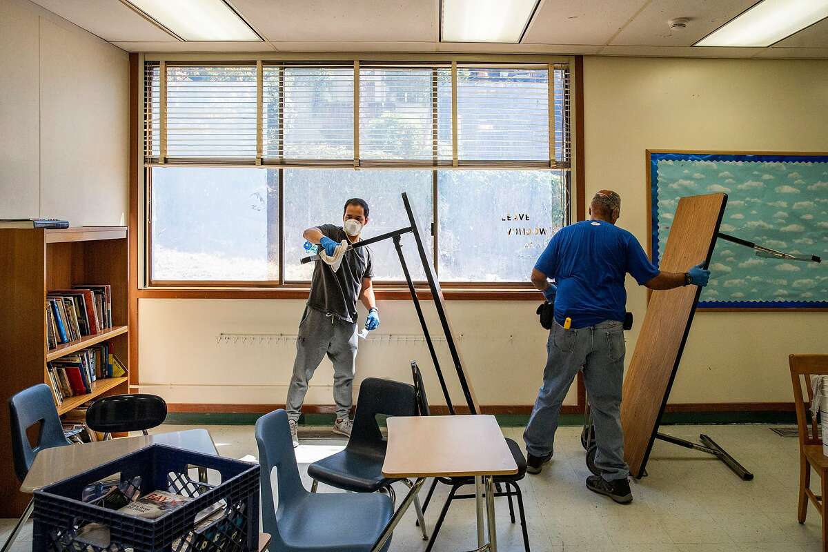 From left: Custodians Orlando Lavarias and Herman Flood clean and sanitize a classroom that will be set up for physical distancing at Westlake Middle School on Friday, July 10, 2020, in Oakland, Calif.