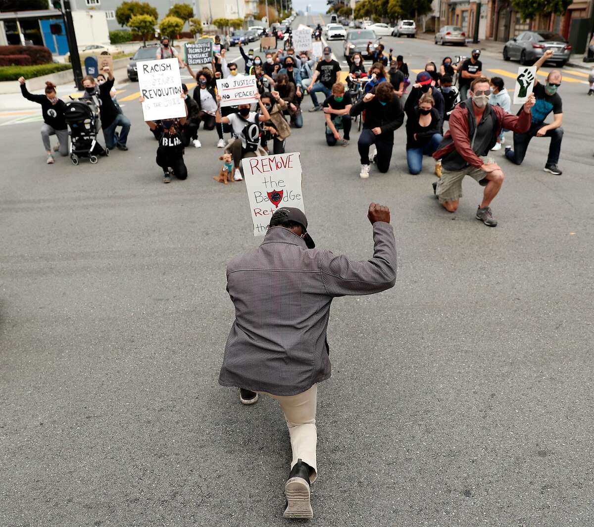 Every 28 Foundation's Don Poisson kneels in the middle of Turk Street as he leads a march from Wallenberg High School through neighborhoods to Richmond Police Station on 6th Avenue in San Francisco, Calif., on Sunday, July 19, 2020. The Police Commission has not voted down the new police budget yet. The Board of Supervisors has heard the city's voice and still have not made a definite move toward disbanding the police.