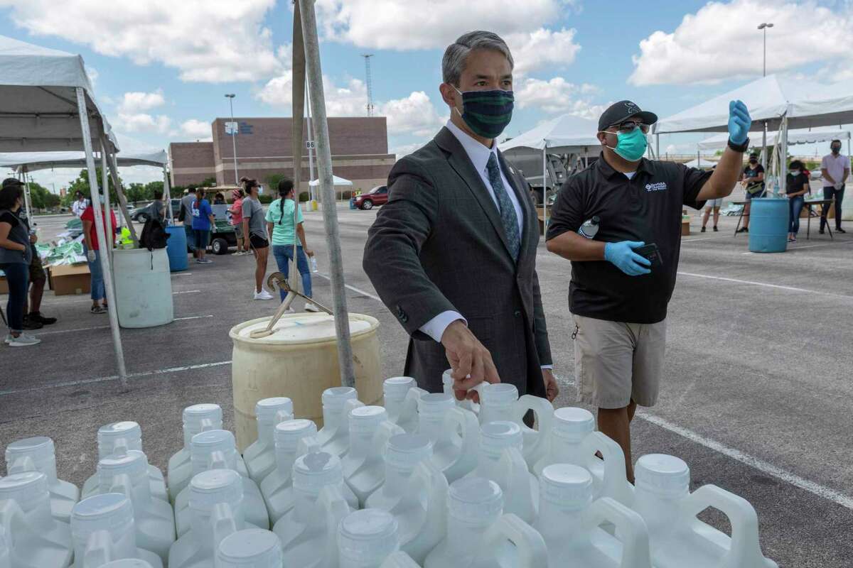 San Antonio mayor Ron Nirenberg, left, hands out sanitizer May 27, 2020, to business owners picking up COVID-19 coronavirus safety supplies during the “Greater. SAfer. Together.” event at the Alamodome while Bobby Rodriguez, South San Antonio Chamber of Commerce vice president of membership, directs vehicles into position.