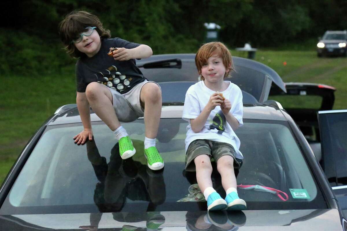 Twins Charlie and Rooney Nashawaty, 6, of Westport, have a snack before the show at the Lachat Town Farm pop-up drive-in movie screening of "Caddyshack" on Sunday, July 19, 2020, in Weston, Conn. "We were one of the first town's to do this," said organizer and farm adviser Anita Dinwoodie. "We thought the farm was one of the most perfect areas to have a movie." The enormous inflatable screen was the backdrop to a question-and-answer session with Nashawaty about "Caddyshack," which has become a cult classic. Carol Baldwin, a documentary film maker and chair of Friends of Lachat, served as interviewer.