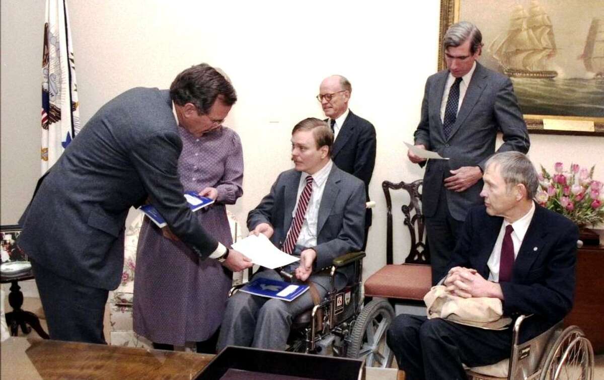 Vice President George H.W. Bush, left, receives a proposal for the Americans with Disabilities Act in 1986 from policy expert Lex Frieden. Also pictured are Jeremiah Milbank, from center left, Boyden Gray and Justin Dart Jr.