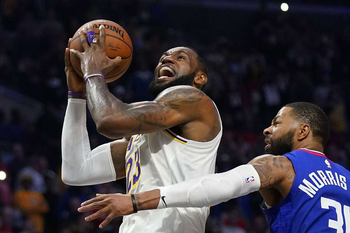 FILE - In this March 8, 2020, file photo, Los Angeles Lakers forward LeBron James, left, shoots as Los Angeles Clippers forward Marcus Morris Sr. defends during the second half of an NBA basketball game in Los Angeles. The NBA is a few weeks from playoff mode, and James has himself and the Lakers squarely in the mix to compete for championship. It is a rare bit of normalcy for a player who appeared in eight consecutive NBA Finals from 2011 through and including 2018, and for a franchise that has won 16 championships. (AP Photo/Mark J. Terrill, File)