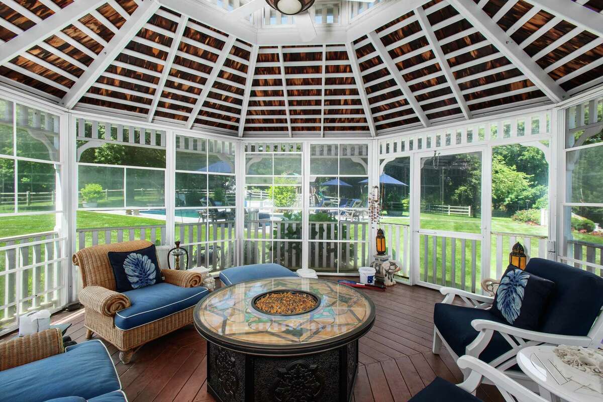 Looking over all the backyard amenities is the screened-in gazebo. Lounge on the expansive granite patio bordered by a fieldstone sitting wall. Swim in the heated Gunite in-ground swimming pool. Dine in the screened-in gazebo or al fresco beneath the pergola, where there is also a built-in Viking grill. Entertaining outside is enhanced by an interior wet bar with a granite counter, glass-front cabinetry, a beverage refrigerator and French doors that open to the patio.