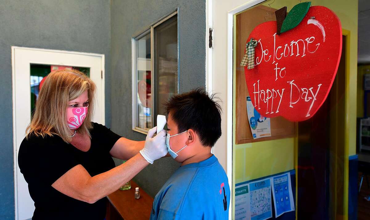 Principal Pam Rasmussen checks the temperature of students on arrival, as per coronavirus guidelines, during summer school sessions at Happy Day School in Monterey Park, California on July 9, 2020. (Frederic J. Brown/AFP/Getty Images/TNS)