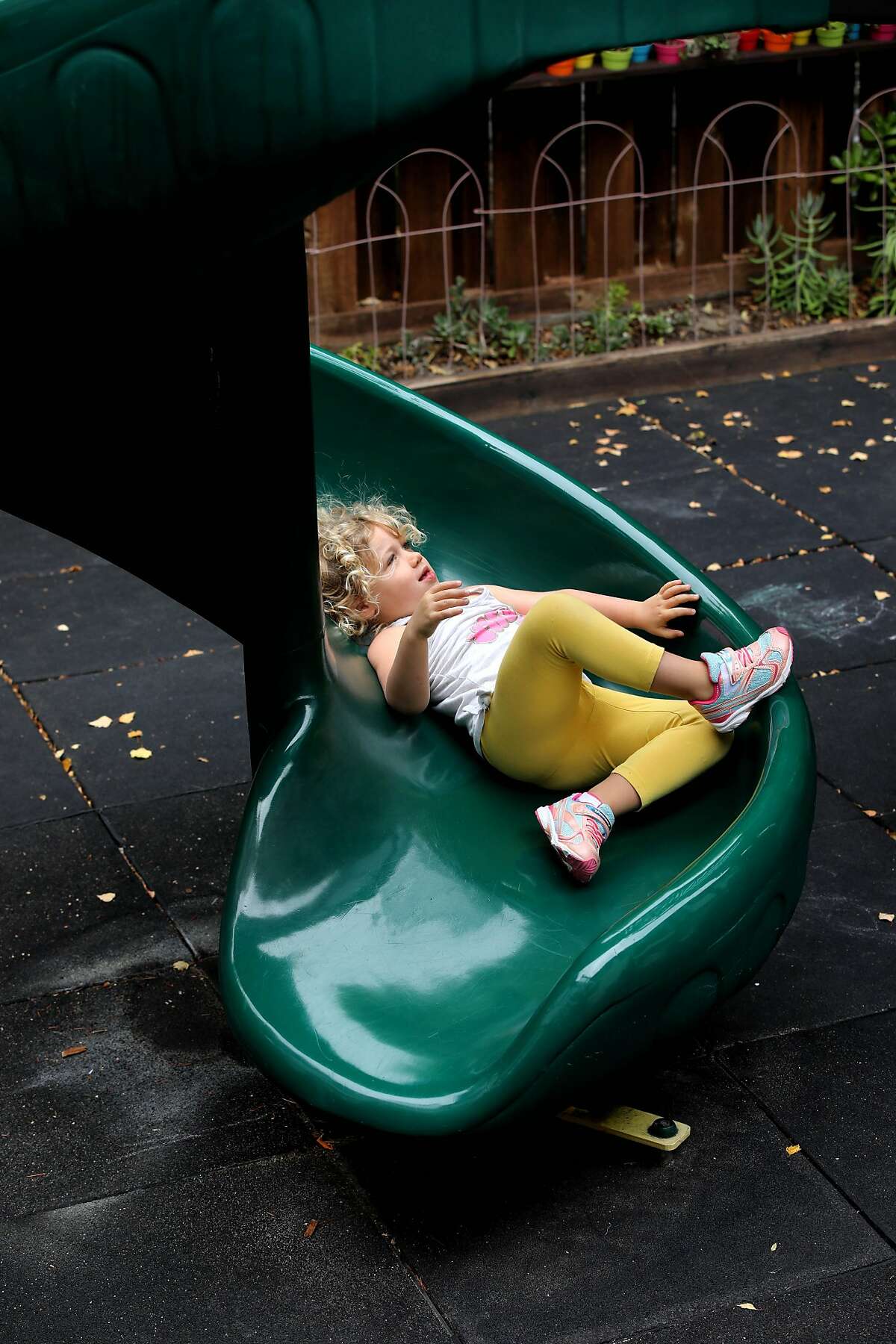 A preschooler comes down a slide at Rockridge Little School on Tuesday, July 21, 2020, in Oakland, Calif. As the pandemic surges and cities and counties stumble through the stop-start process of reopening, the childcare industry -- a vital crutch for many working parents -- appears to be on the verge of collapse. A new report from UC Berkeley serves as a grim I-told-you-so moment for centers and other providers who warned in the spring that long closures, confusing guidelines and heavy restrictions would devastate their already precarious financial models. Parents need childcare to return to work, and many may seek these programs now to fill in for closed public schools. But providers are closing or barely hanging on. Of 953 childcares surveyed for the report, 21% said they had missed a rent or mortgage payment during the pandemic, 81% are operating with fewer children, and 80% have higher cleaning costs.