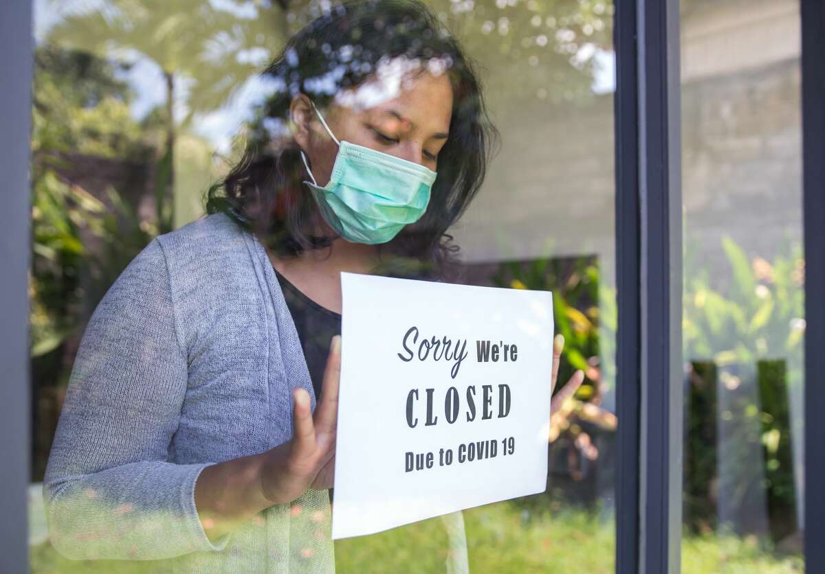 A restaurant owner puts a "closed" poster on a door window because of the COVID-19 pandemic.