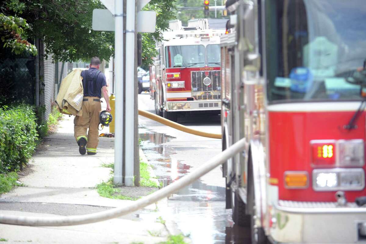 A firefighter walks back to his firetruck after putting out a fire inside a passenger van behind a house on Atlantic Street in Stamford on July 26, 2018.