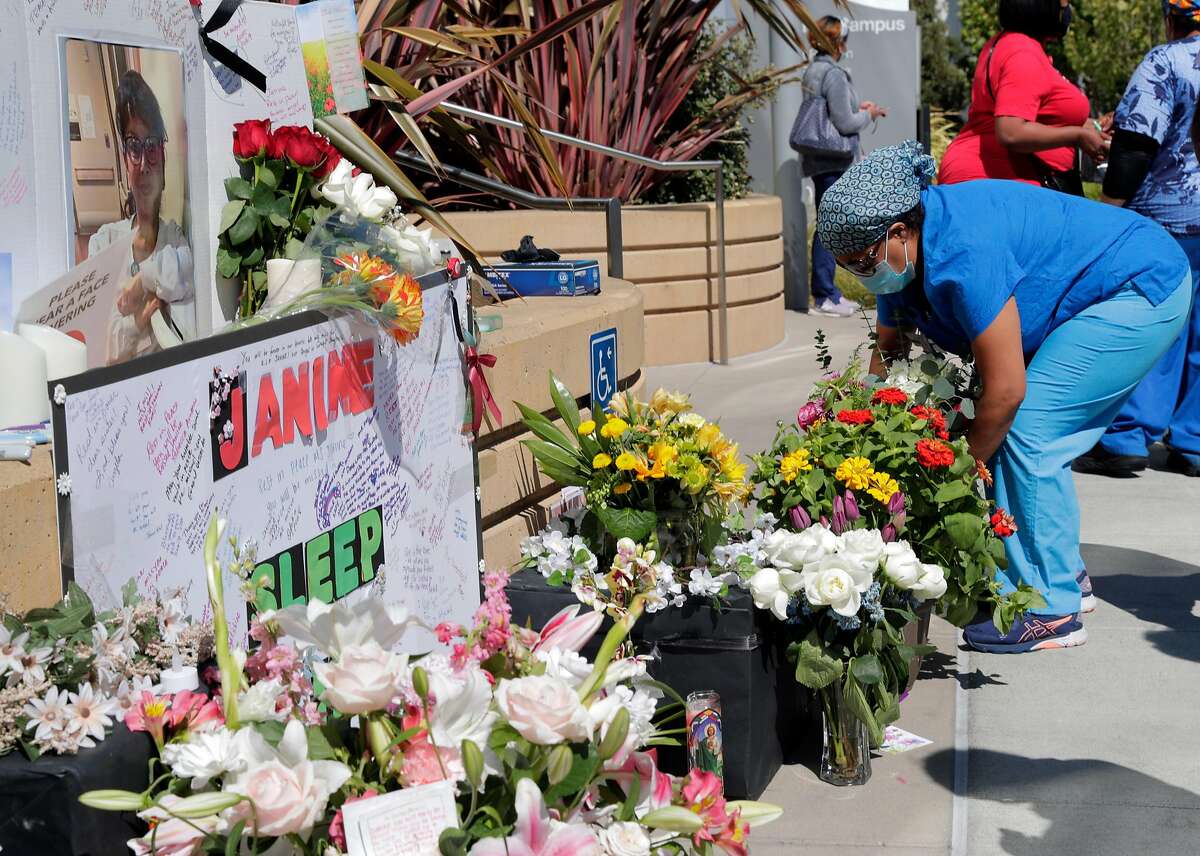 Myra Juarez leaves a bouquet of flowers at a memorial during a vigil for nurse Janine Paiste-Ponder, who died of COVID-19 after working with patients with the disease at Alta Bates Summit Medical Center in Oakland , Calif., on Tuesday, July 21, 2020.