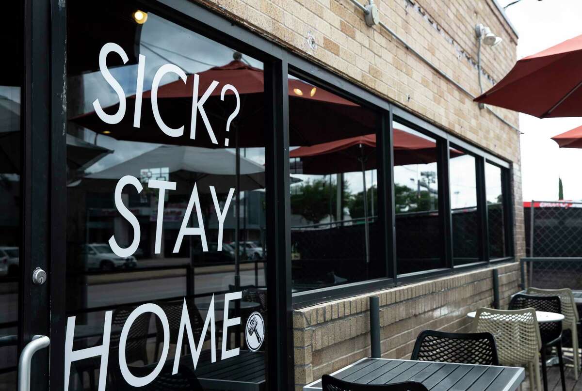 Blacksmith coffeeshop has the "Sick? Stay Home" sign on its window during the coronavirus pandemic Monday, July 20, 2020, in Houston.