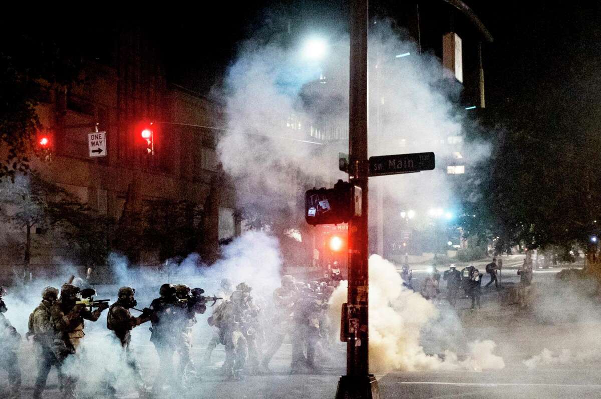 Federal agents use crowd- control munitions to disperse protesters near the federal courthouse in Portland, Ore., on Monday. In cities where mobs aren’t trying to burn down symbols of the U.S. justice system, there’s no enhanced presence of federal officers.